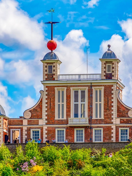 Royal Observatory Greenwich with iconic red time ball against a cloudy sky.