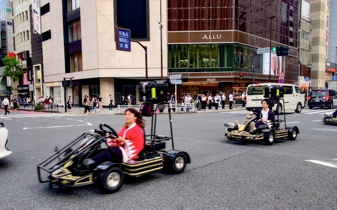 Street karts driving through a busy intersection in Tokyo.