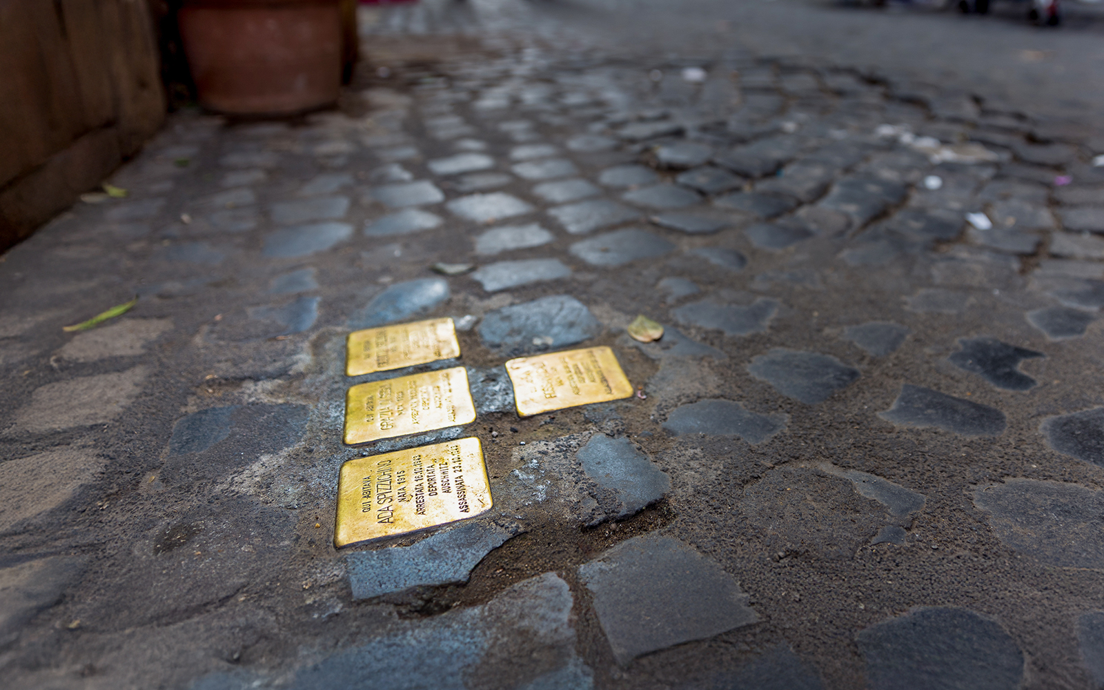 Stumbling stones embedded in cobblestone street in Rome.