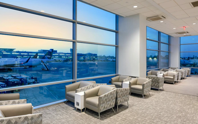 Aspire Lounge seating area with airport runway view at San Diego International Airport.