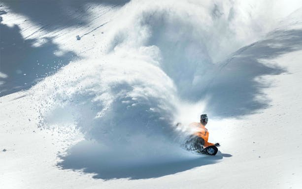 Snowboarder carving through fresh powder on a mountain slope, Ikon Pass.
