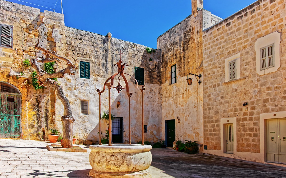 Historic courtyard in Mdina with stone walls and an old well, Malta.