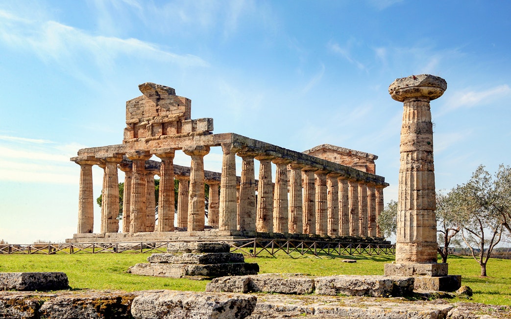 Temple of Athena in Paestum with ancient columns under a clear blue sky.