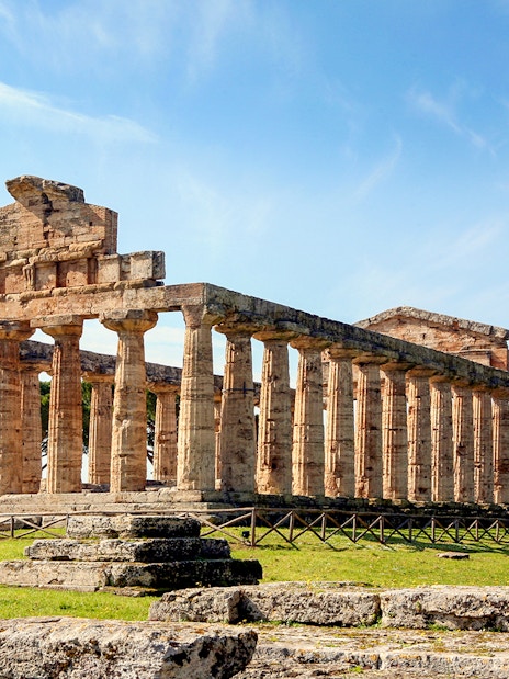 Temple of Athena in Paestum with ancient columns under a clear blue sky.