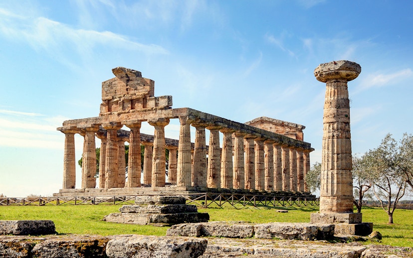 Temple of Athena in Paestum with ancient columns under a clear blue sky.
