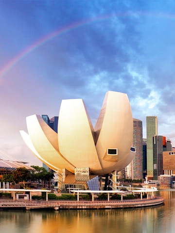 ArtScience Museum in Singapore with city skyline and rainbow in the background.