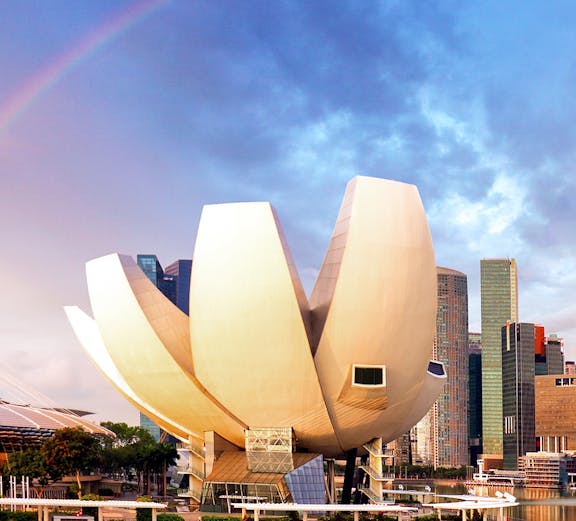 ArtScience Museum in Singapore with city skyline and rainbow in the background.
