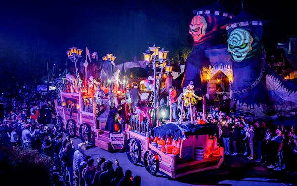 Parade with Halloween floats and performers at Astérix Parc, France, during special event.