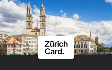 Grossmünster church towers over Zürich's historic buildings under a blue sky.