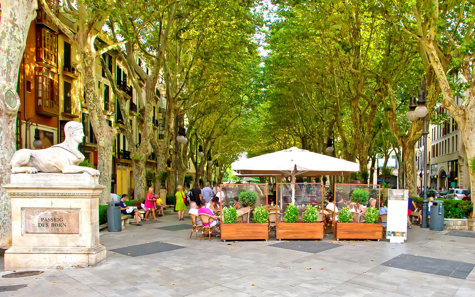 Passeig des Born street view in Mallorca with people walking and enjoying outdoor cafes.