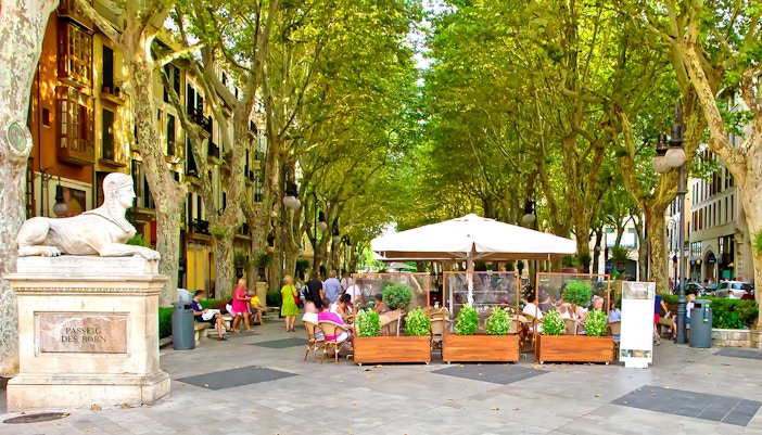 Passeig des Born street view in Mallorca with people walking and enjoying outdoor cafes.