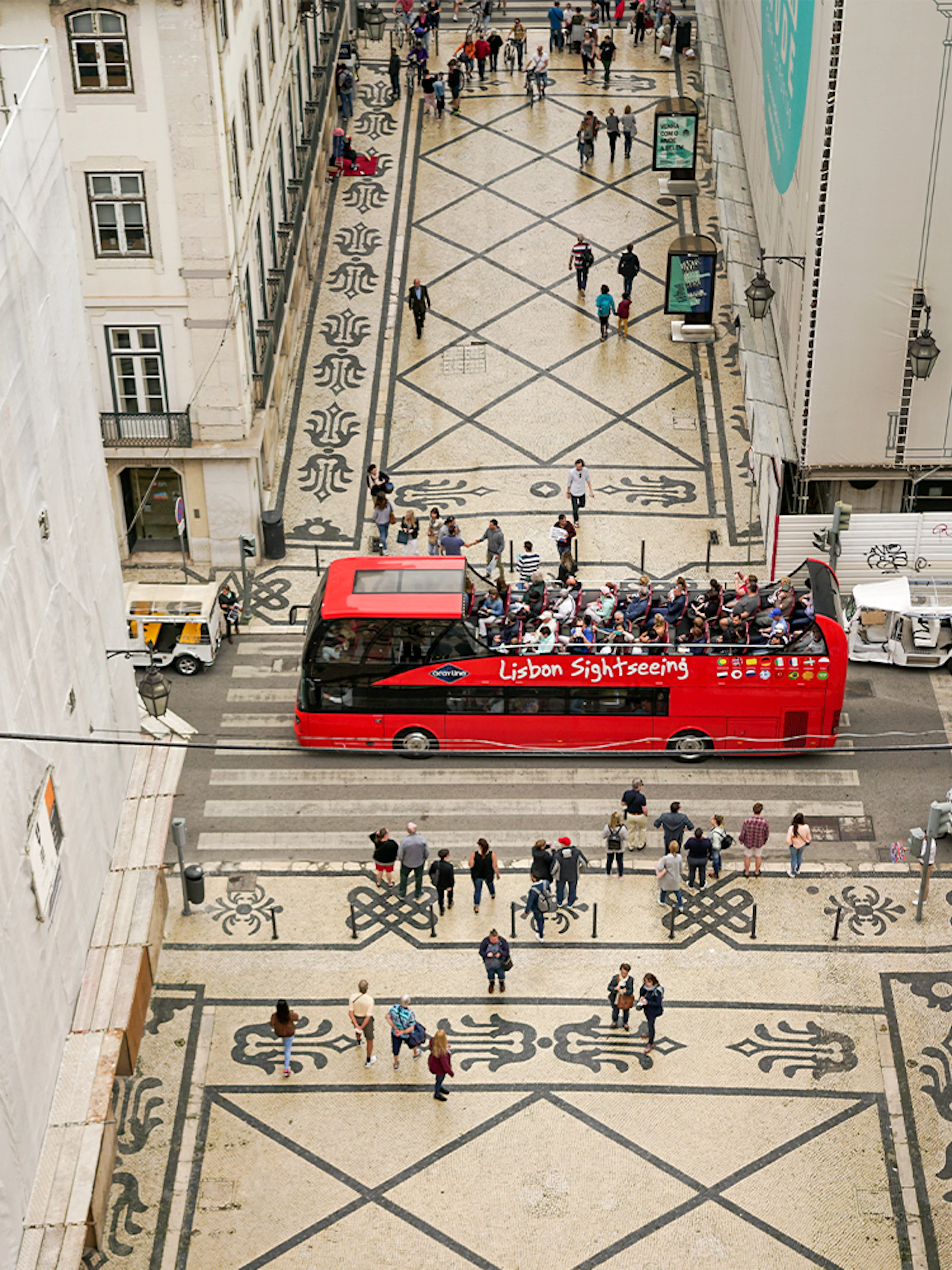Lisbon hop-on hop-off bus on a patterned street near São Jorge Castle.