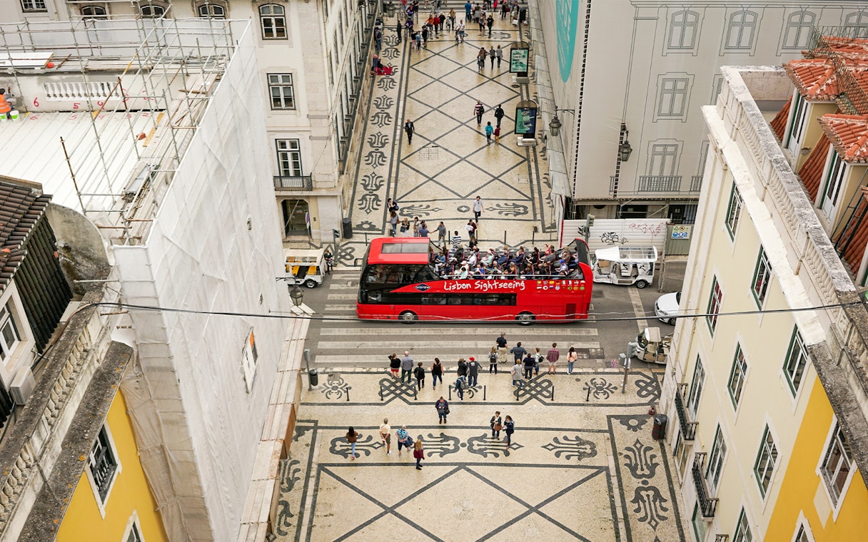 Lisbon hop-on hop-off bus on a patterned street near São Jorge Castle.