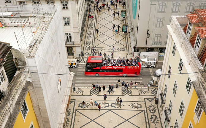Lisbon hop-on hop-off bus on a patterned street near São Jorge Castle.