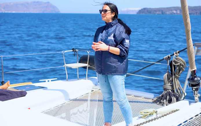 Tour guide speaking to guests on a catamaran during Santorini Joy Daytime Cruise.