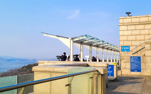 Observation deck overlooking the DMZ with tourists using binoculars, Paju, South Korea.