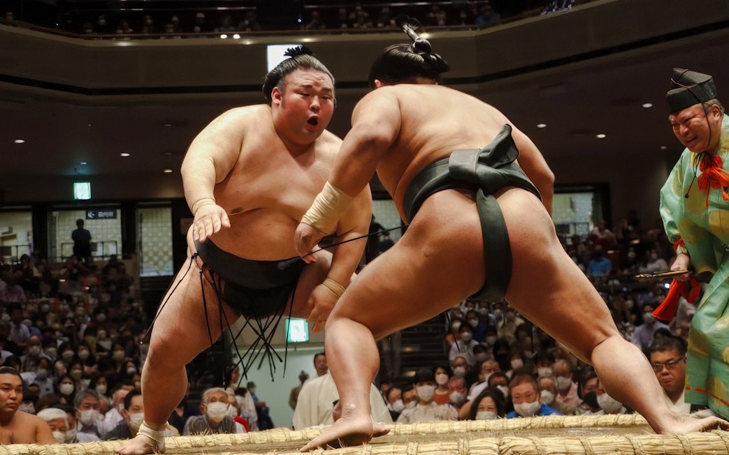 Sumo wrestlers competing in a crowded arena in Japan.