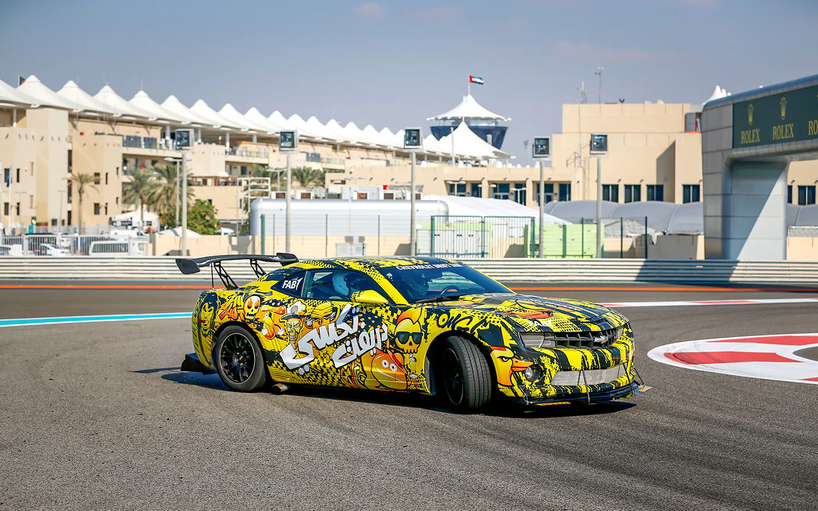 A yellow-and-black Chevrolet Camaro drift taxi cornering on the Yas Marina Circuit.