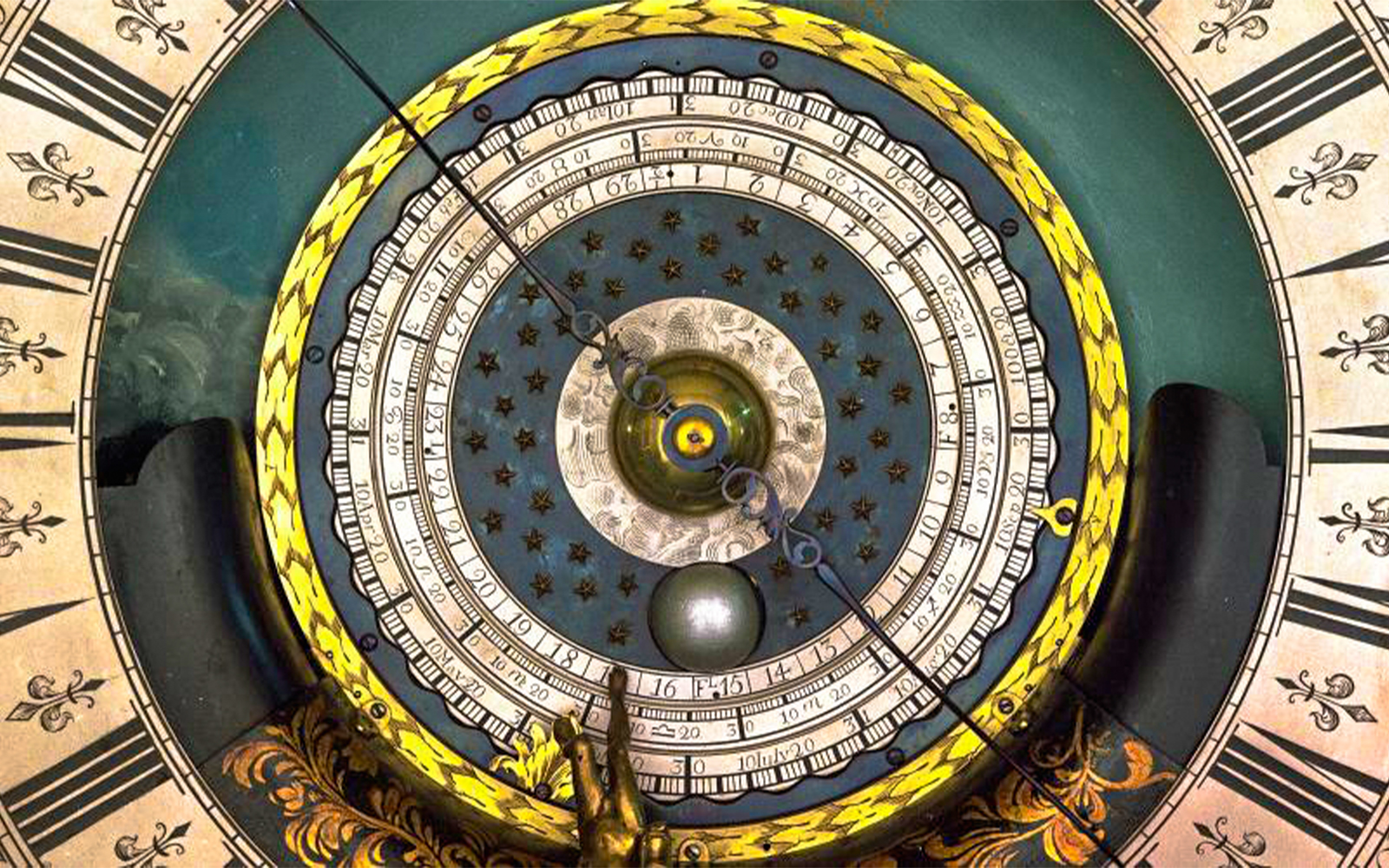 Astronomical clock face at Royal Observatory Greenwich, featuring intricate dials and celestial motifs.