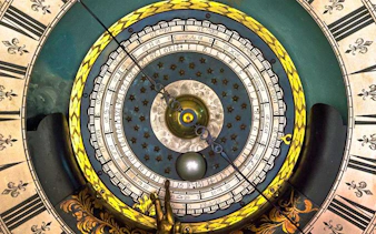 Astronomical clock face at Royal Observatory Greenwich, featuring intricate dials and celestial motifs.