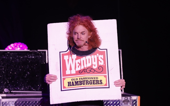 Performer holding a Wendy's sign during Carrot Top show in Las Vegas.