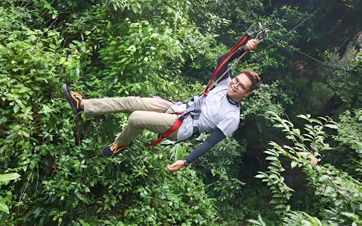 Person ziplining through lush forest at Skytrex Adventure Langkawi.