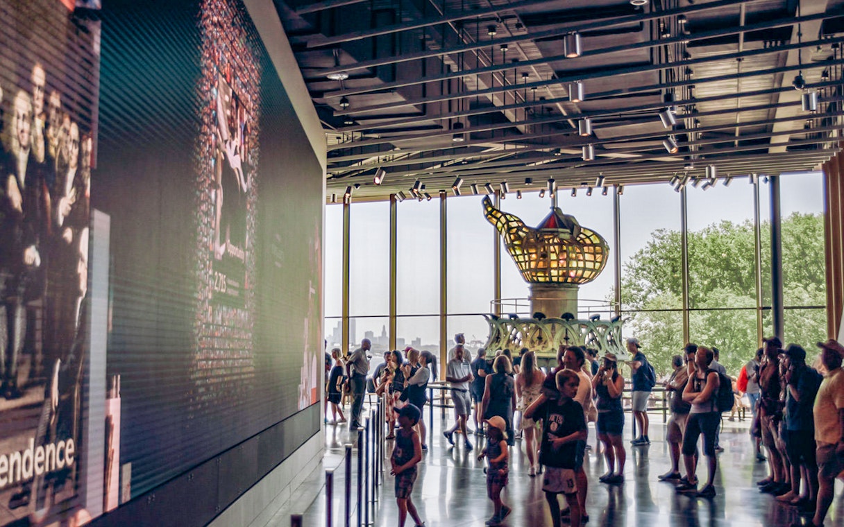 Visitors inside the Statue of Liberty Museum viewing the original torch exhibit.