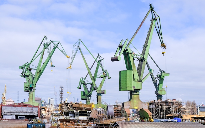 Cranes at Gdansk Shipyard in Poland against a cloudy sky.