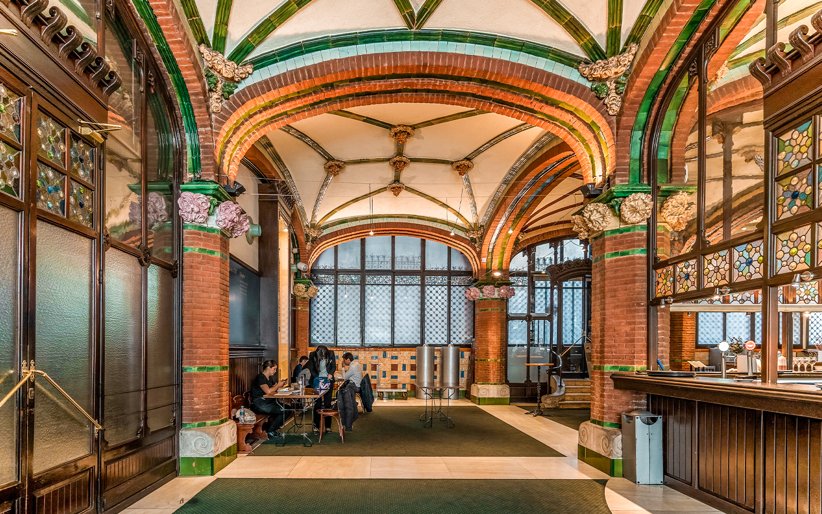 Hall inside Palau de la Musica Catalana with stained glass and ornate arches.