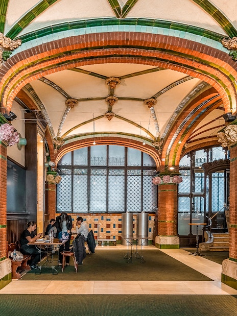 Hall inside Palau de la Musica Catalana with stained glass and ornate arches.