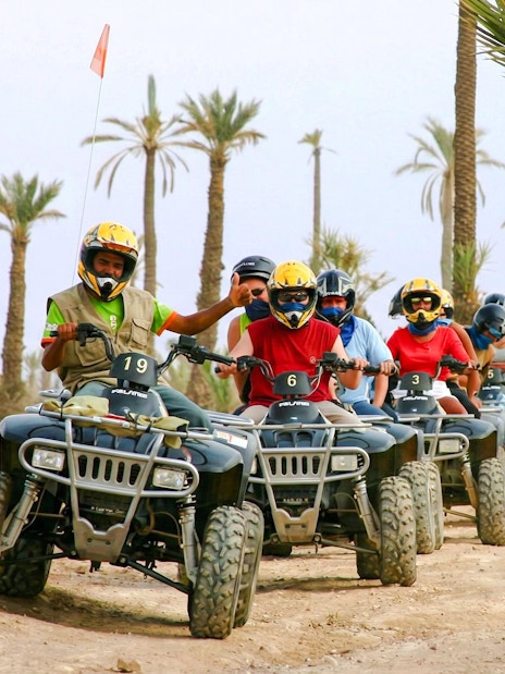 Group riding quad bikes through Palmeraie desert landscape.