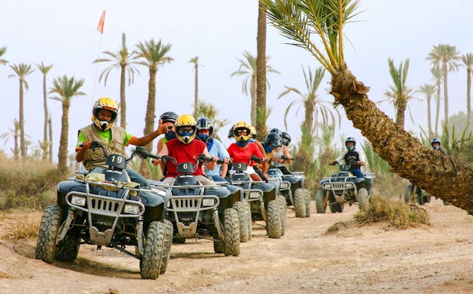 Group riding quad bikes through Palmeraie desert landscape.