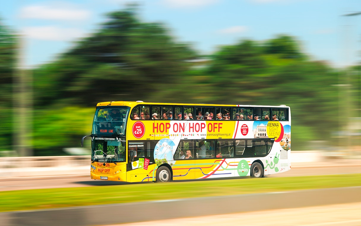 Vienna sightseeing hop-on hop-off bus driving through city.