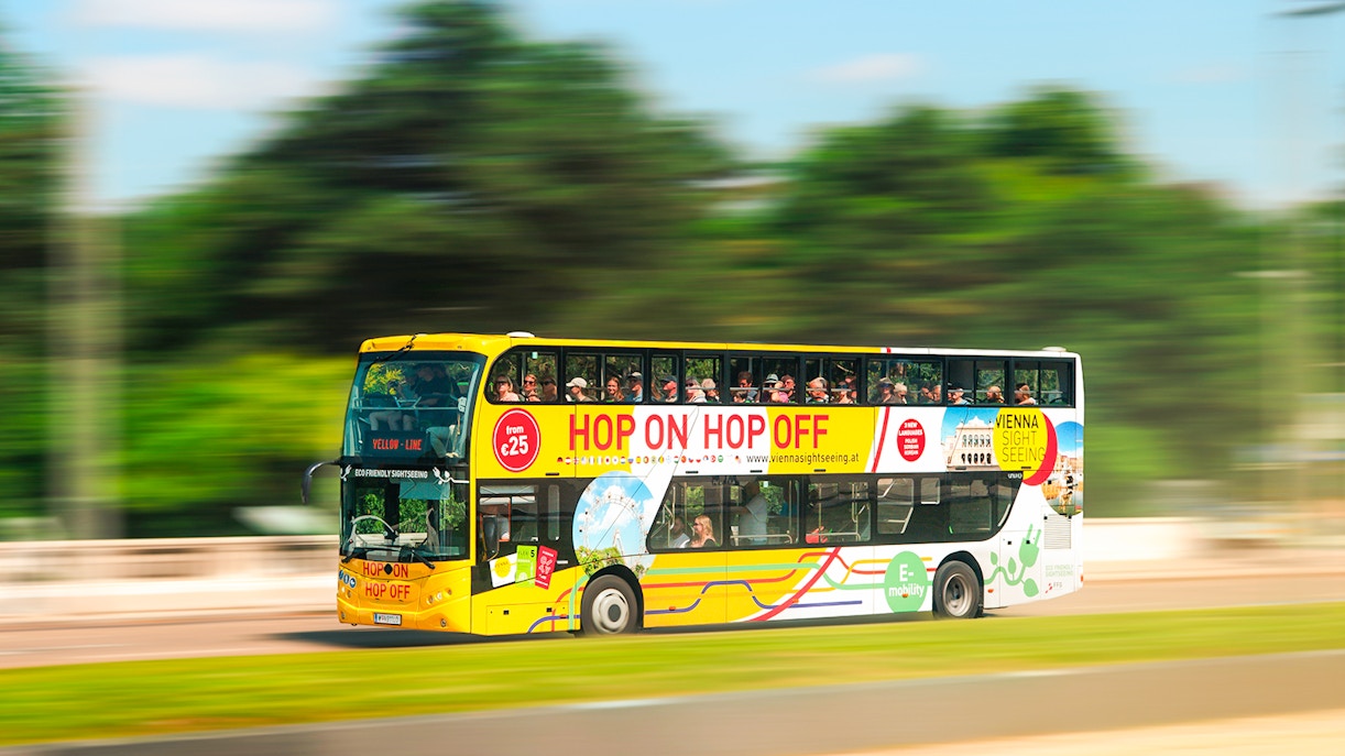 Vienna sightseeing hop-on hop-off bus driving through city.