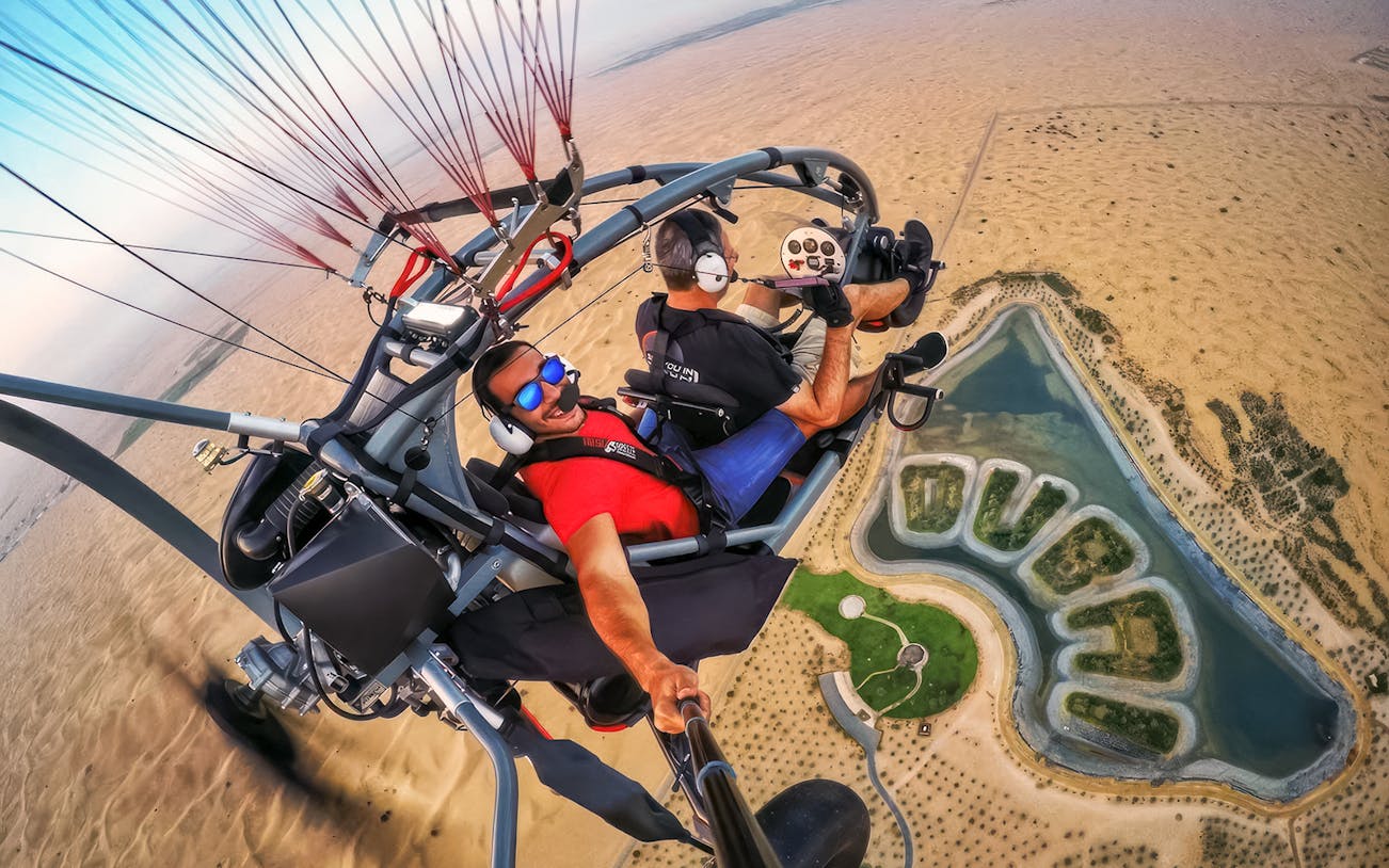 Guests flying over desert landscape on a paramotor adventure tour.