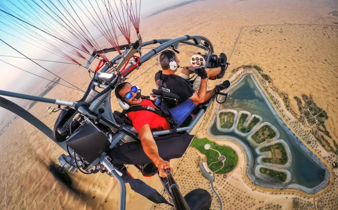 Guests flying over desert landscape on a paramotor adventure tour.