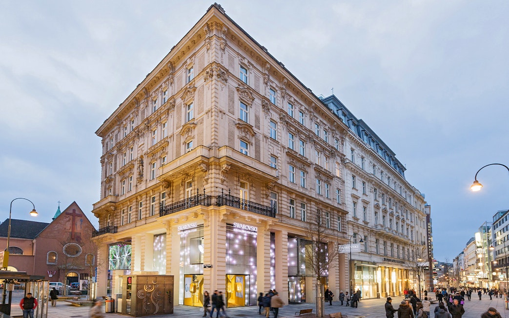Swarovski House in Vienna with illuminated storefront on a busy street.
