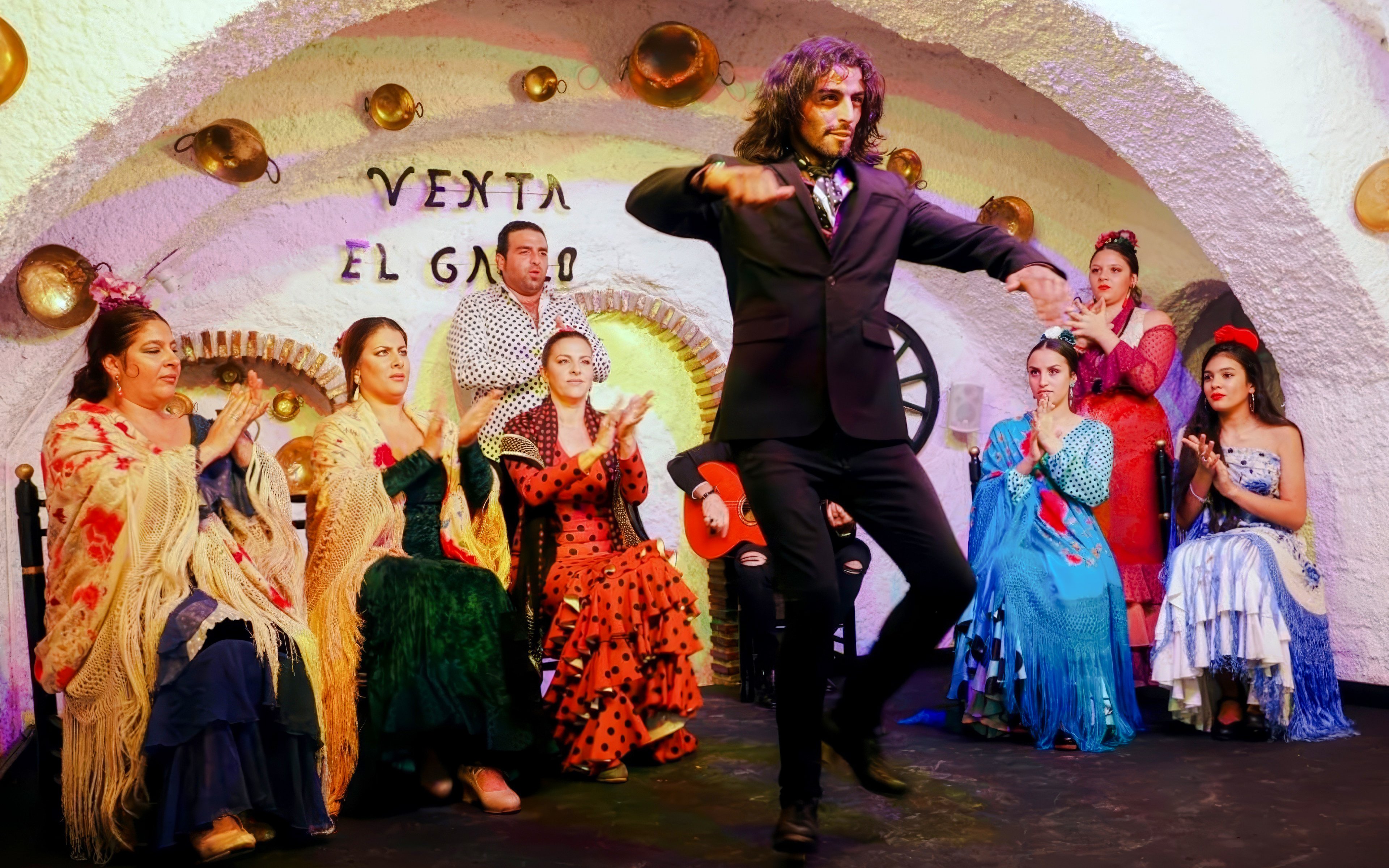 Flamenco dancer performing at Venta el Gallo with musicians and audience clapping.