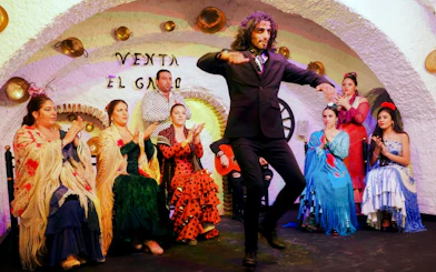 Flamenco dancer performing at Venta el Gallo with musicians and audience clapping.