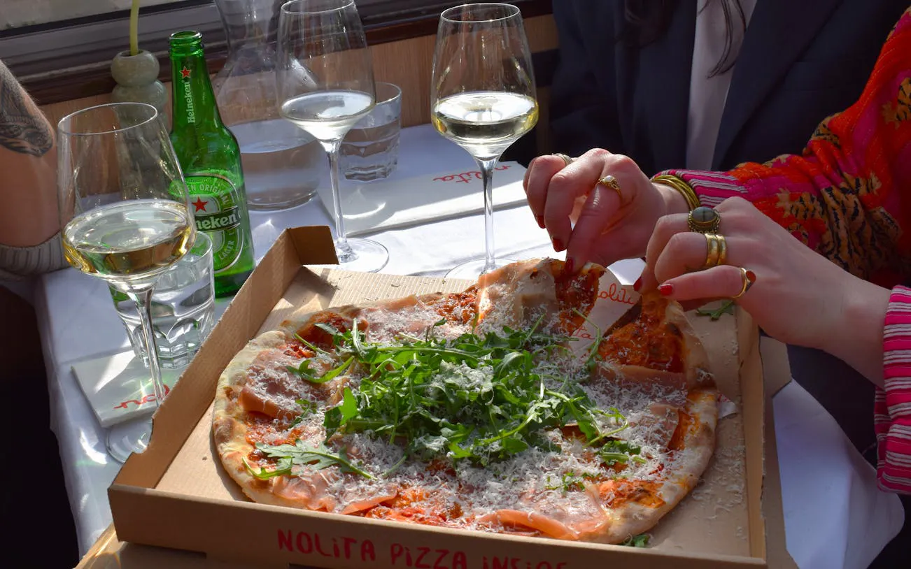 Nolita pizza served on Haarlem canal dinner cruise with wine glasses on table.