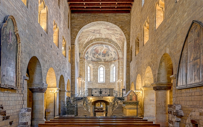Interior of Basilica of St George with arched stone walls and ornate frescoed ceiling.