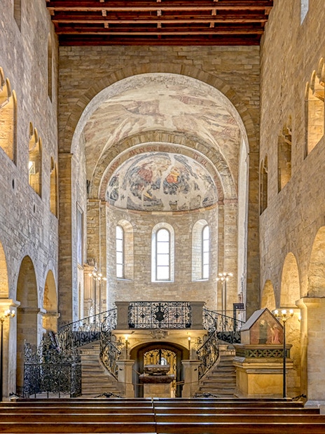 Interior of Basilica of St George with arched stone walls and ornate frescoed ceiling.