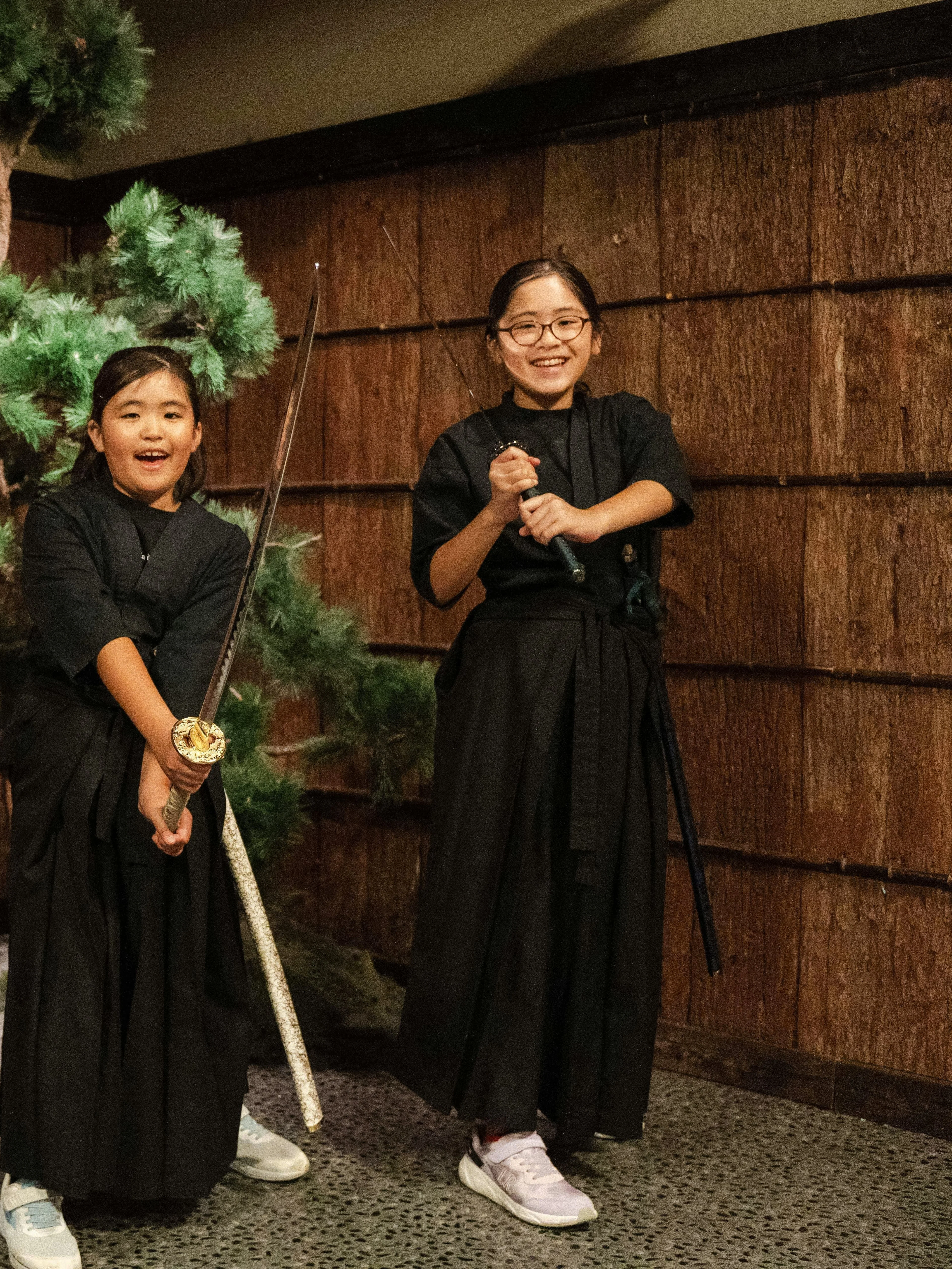 Tourists with swords in front of bonsai tree at Samurai Experience, Shinjuku.