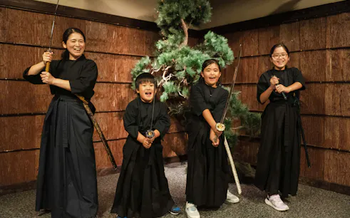 Tourists with swords in front of bonsai tree at Samurai Experience, Shinjuku.