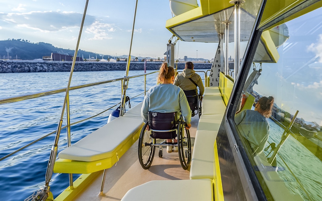 Eco catamaran cruise with passengers in wheelchairs enjoying coastal views.