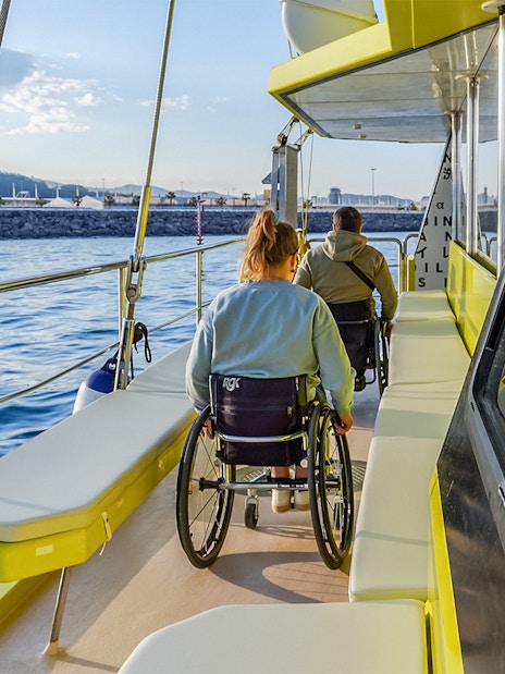 Eco catamaran cruise with passengers in wheelchairs enjoying coastal views.