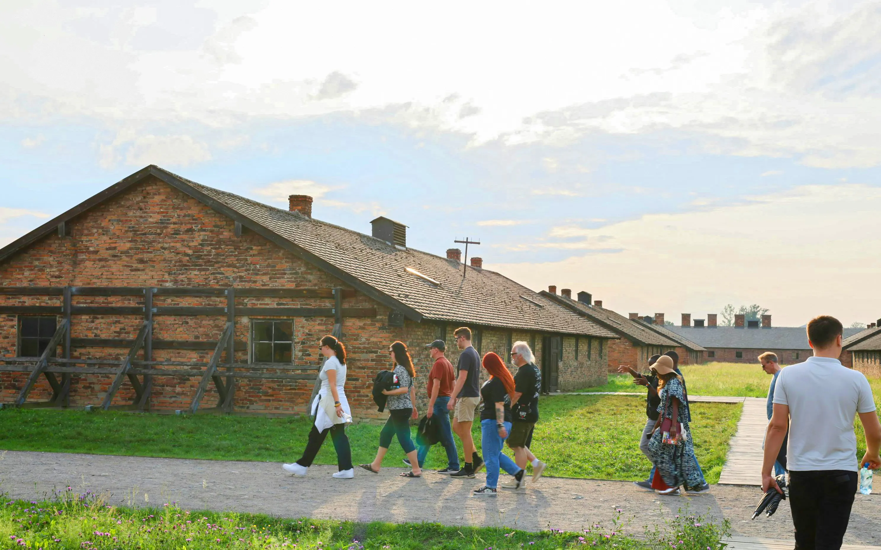 Tour group walking past brick barracks at Auschwitz-Birkenau, Krakow guided tour.