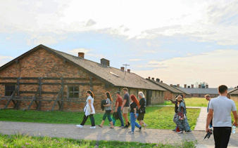 Tour group walking past brick barracks at Auschwitz-Birkenau, Krakow guided tour.
