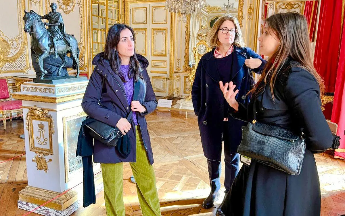 Tour group in the King's Private Apartments at Palace of Versailles with guide explaining statue.