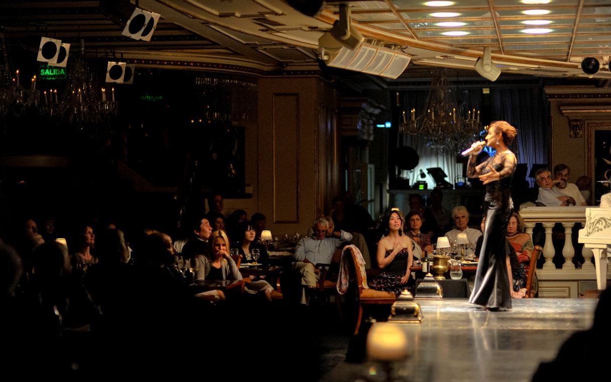 Performer singing at Gala Tango Show in Buenos Aires, audience watching attentively.